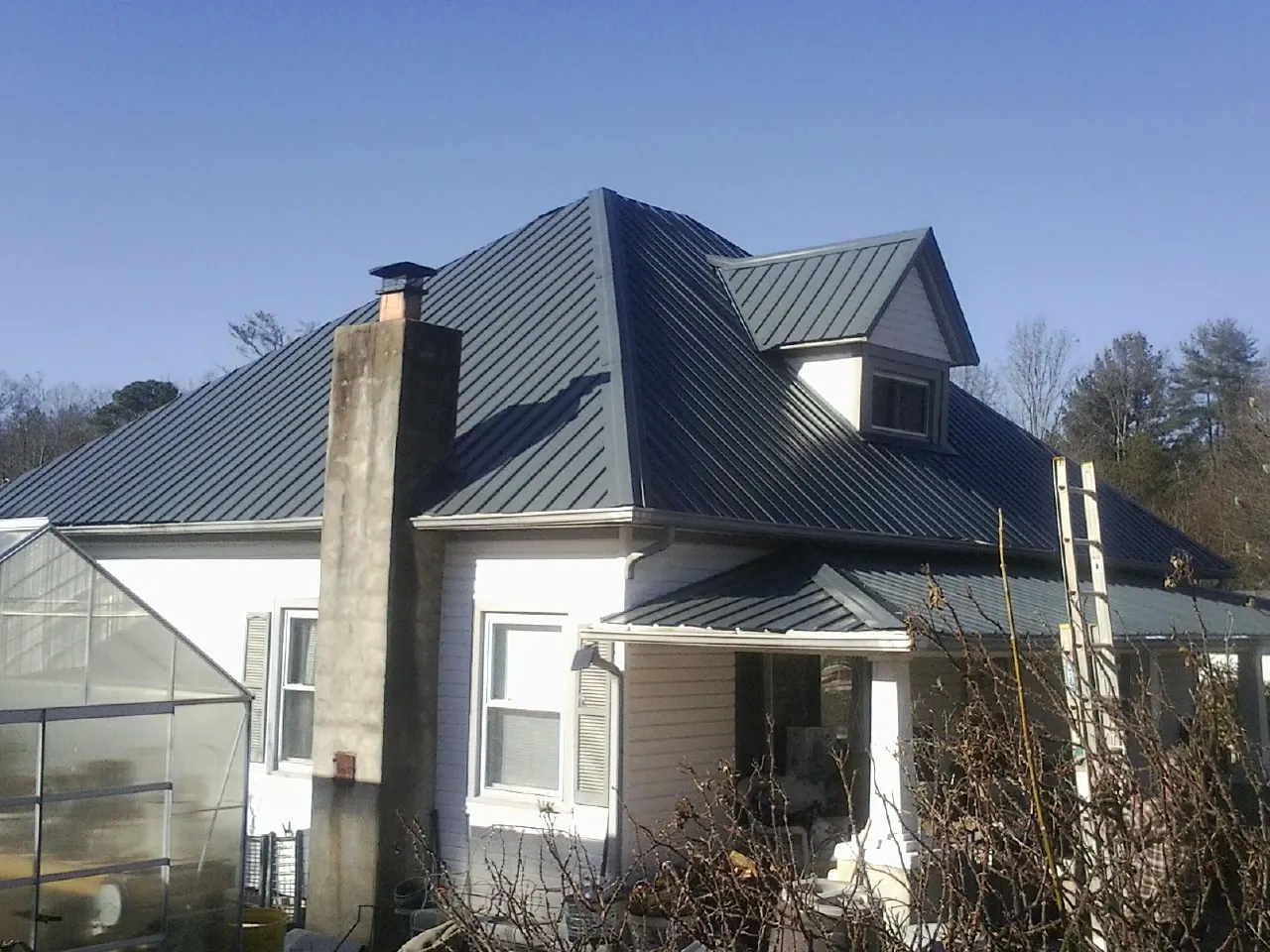 Dark blue standing seam metal roof on a white farmhouse with dormer — Slate & Tile Roof Repair by Roofing Brothers in Chewelah