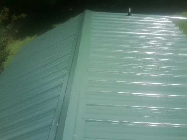 New green metal panels meeting at the ridge of a roof — Flat Roof Repair work by our crew in Chewelah