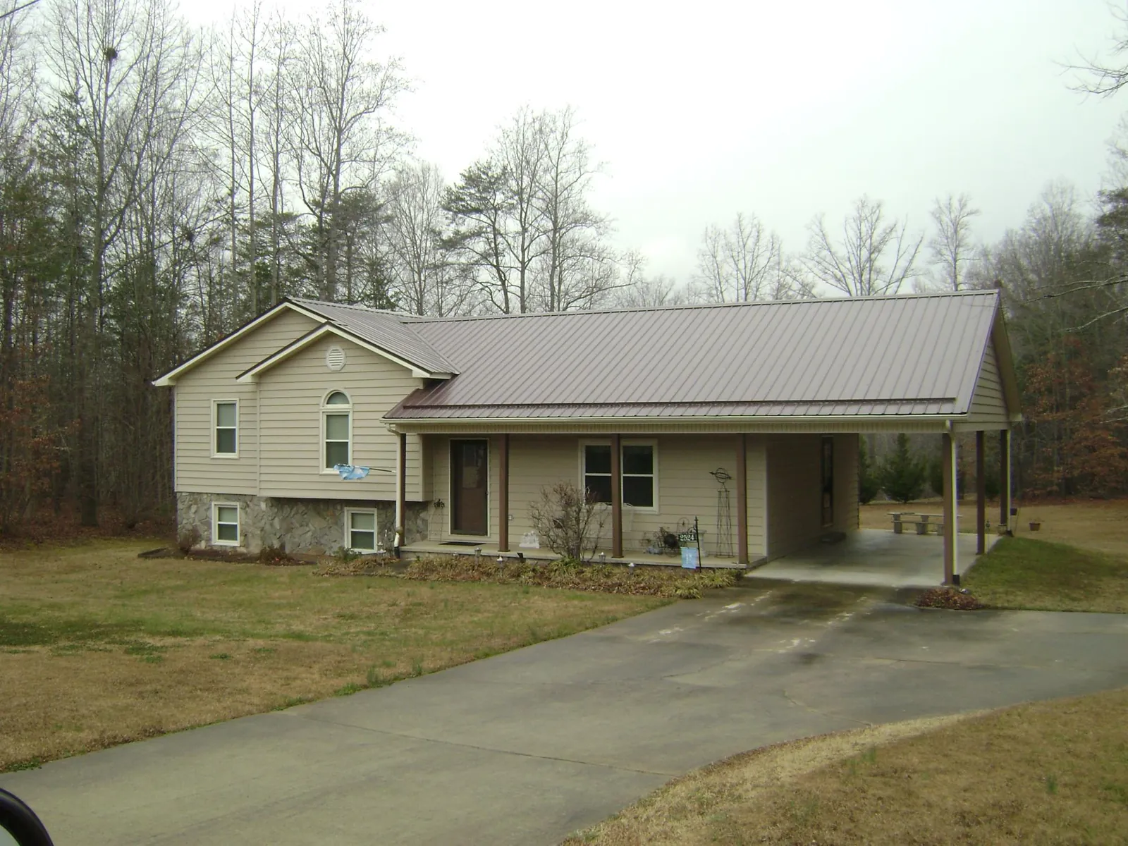 Brown metal roof on a tan split level home with an attached carport in Chewelah
