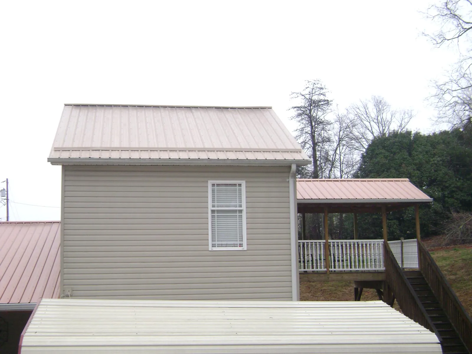 Tan metal roofs on a two story addition and attached porch, from a Roof Replacement job in Chewelah